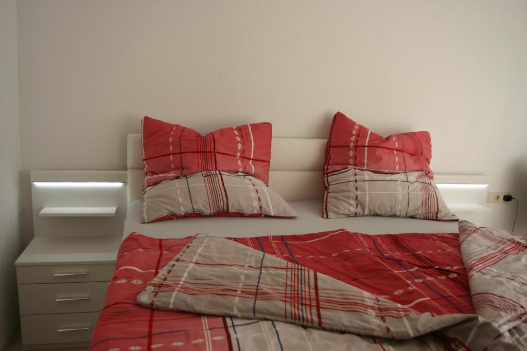 a bedroom with a bed with red comforter and pillows at ApartmentBuyMetzingen in Riederich