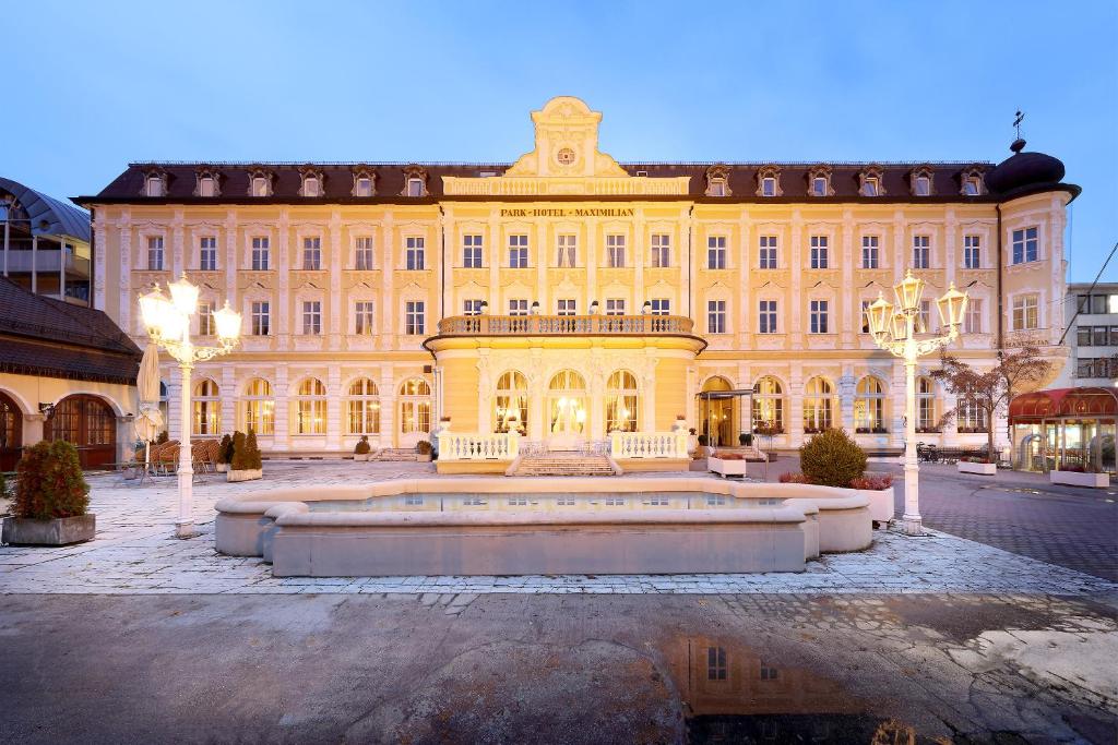 un grand bâtiment jaune avec une fontaine devant lui dans l'établissement Eurostars Park Hotel Maximilian, à Ratisbonne