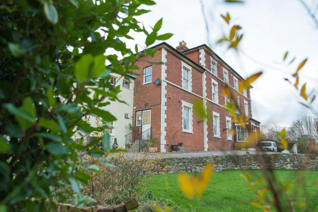 a large brick building on a grassy field at The Lodge at Heathfield in Ledbury