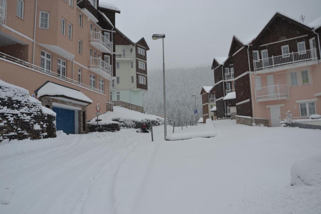 een met sneeuw bedekte straat in een stad met gebouwen bij Apartmány pod horizontem in Pec pod Sněžkou