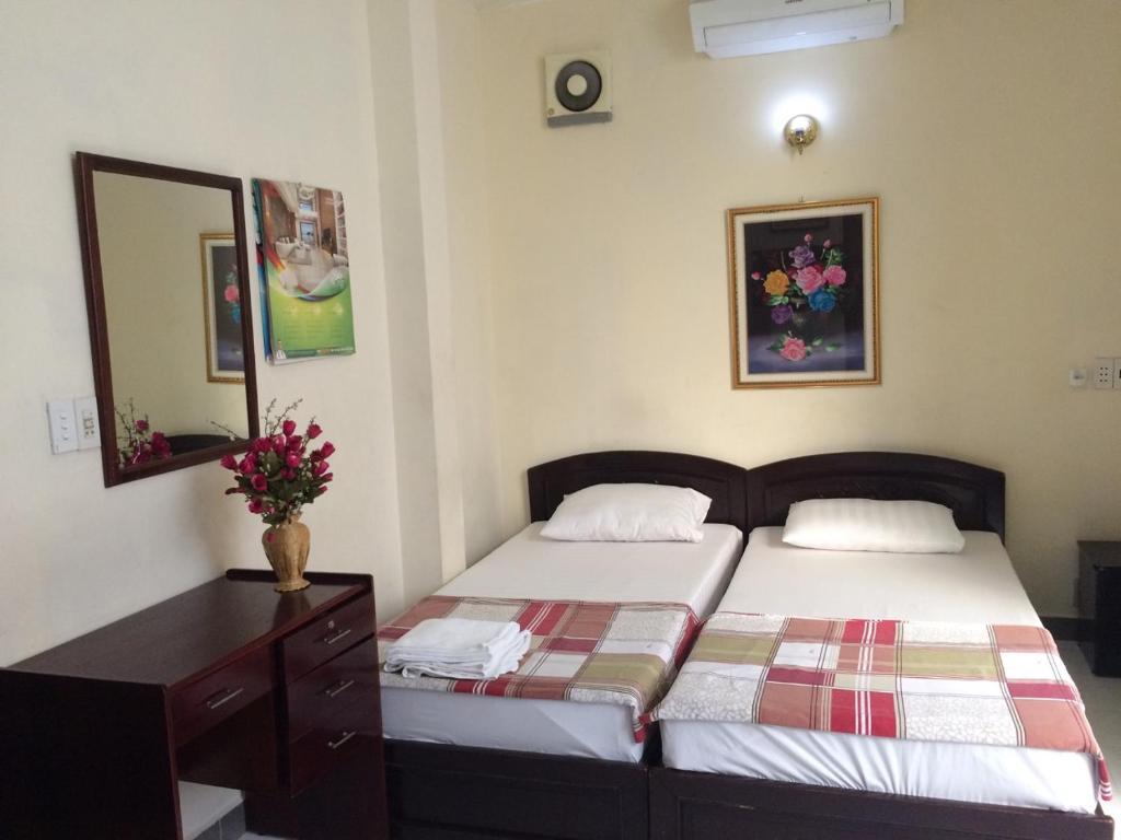a bedroom with two beds and a dresser and a mirror at Giang Hotel in Ho Chi Minh City
