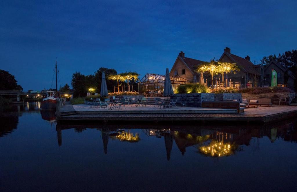 a building with lights on the water at night at Hotel Marenland Winsum in Winsum