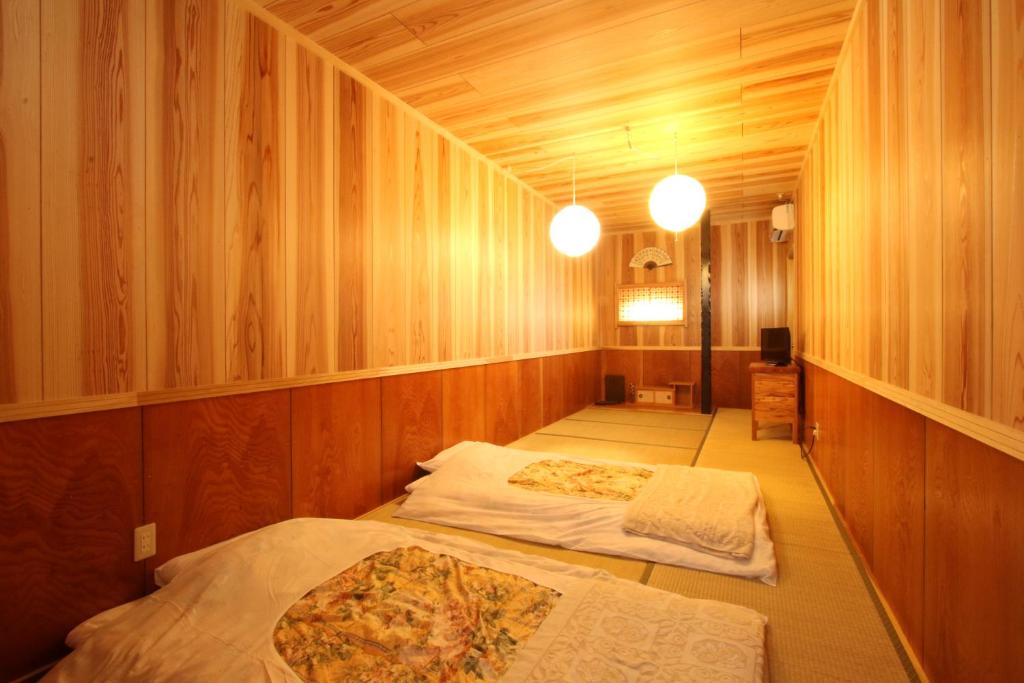2 Betten in einem Zimmer mit Holzwänden in der Unterkunft Ikkyu For Backpackers 19 in Hitoyoshi