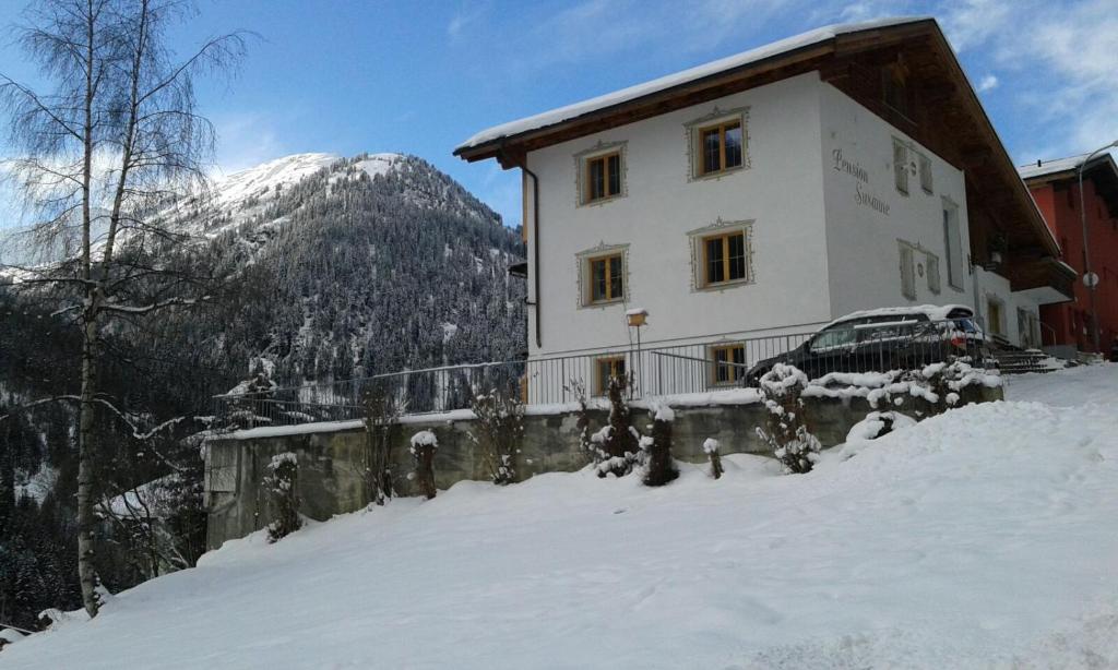 ein Haus im Schnee vor einem Berg in der Unterkunft Pension Susanne in Sankt Anton am Arlberg
