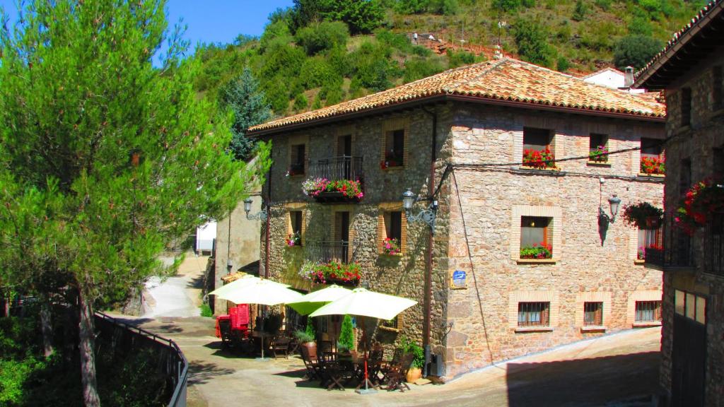 un edificio con mesas y sombrillas delante en Hotel La Posada de Villalangua, en Villalangua