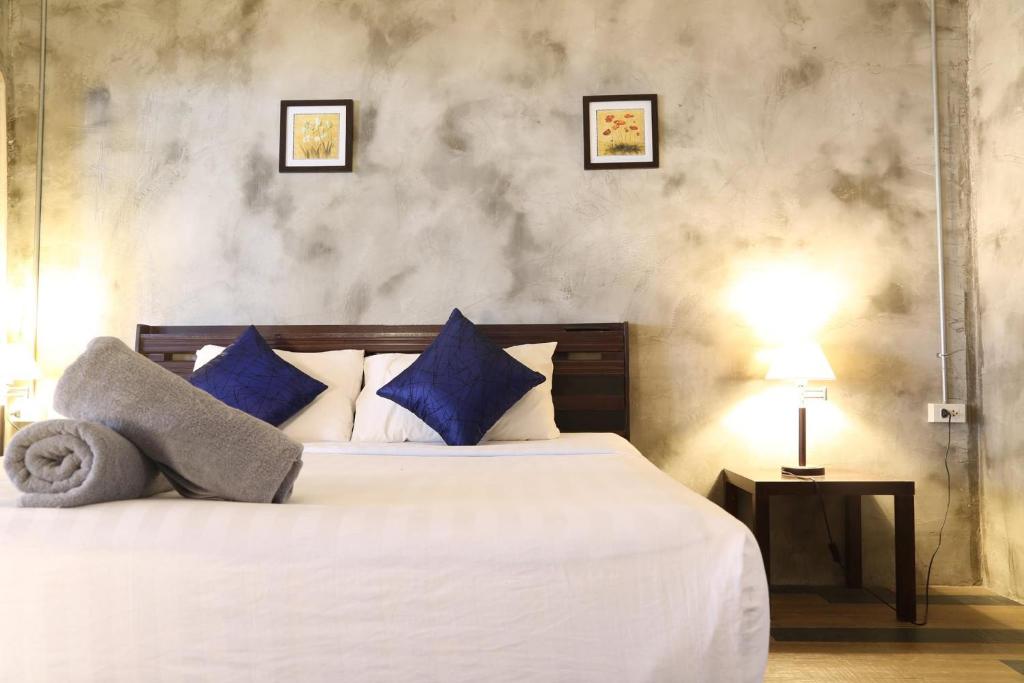 - une chambre avec un grand lit blanc et des oreillers bleus dans l'établissement Crescent Bay Resort, à Ko Samet