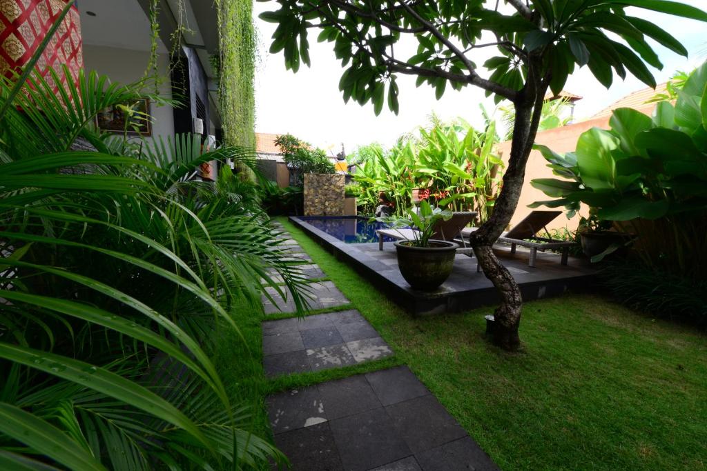 a garden with plants and a patio with a tree at Surya Guest House Sanur in Sanur