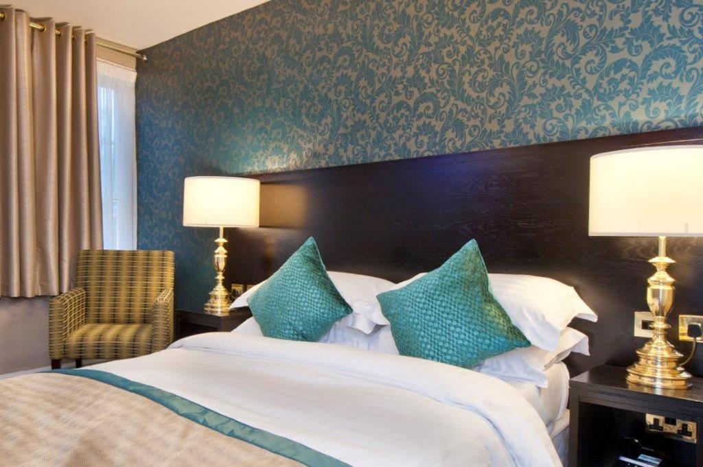a bedroom with a large bed with blue and white pillows at Globe Hotel Wetherspoon in King's Lynn