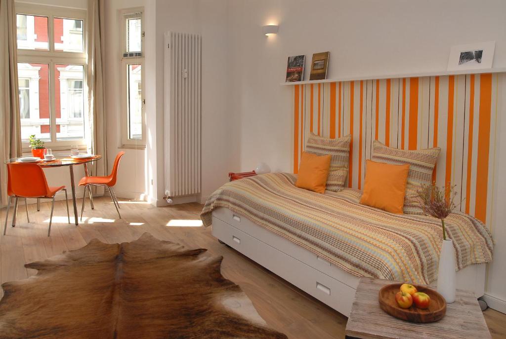 a bedroom with a large bed with orange pillows and a table at Düsselapp in Düsseldorf