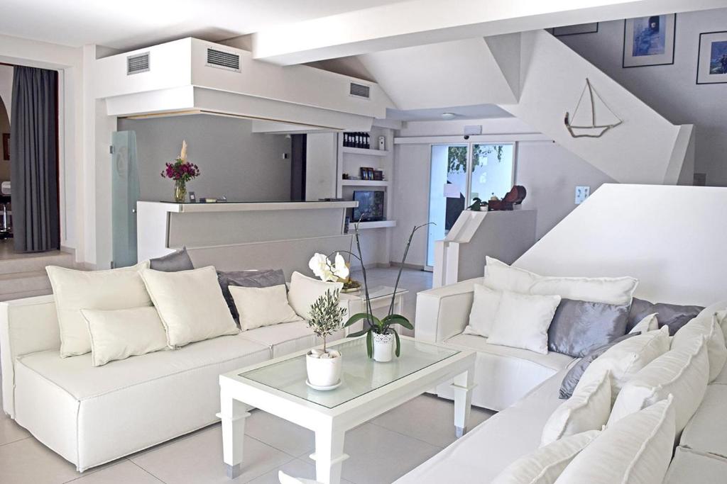 a white living room with white couches and a table at Aegialis Hotel & Spa in Aegiali