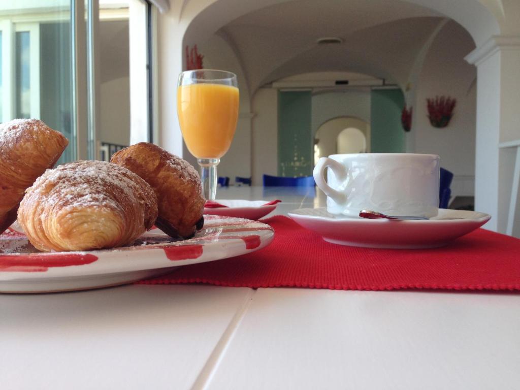 a table with a plate of pastries and a glass of orange juice at Hotel Le Terrazze in Conca dei Marini