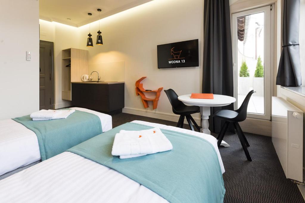ポズナンにあるApartamenty Wodna 13のベッド2台とテーブルが備わるホテルルームです。
