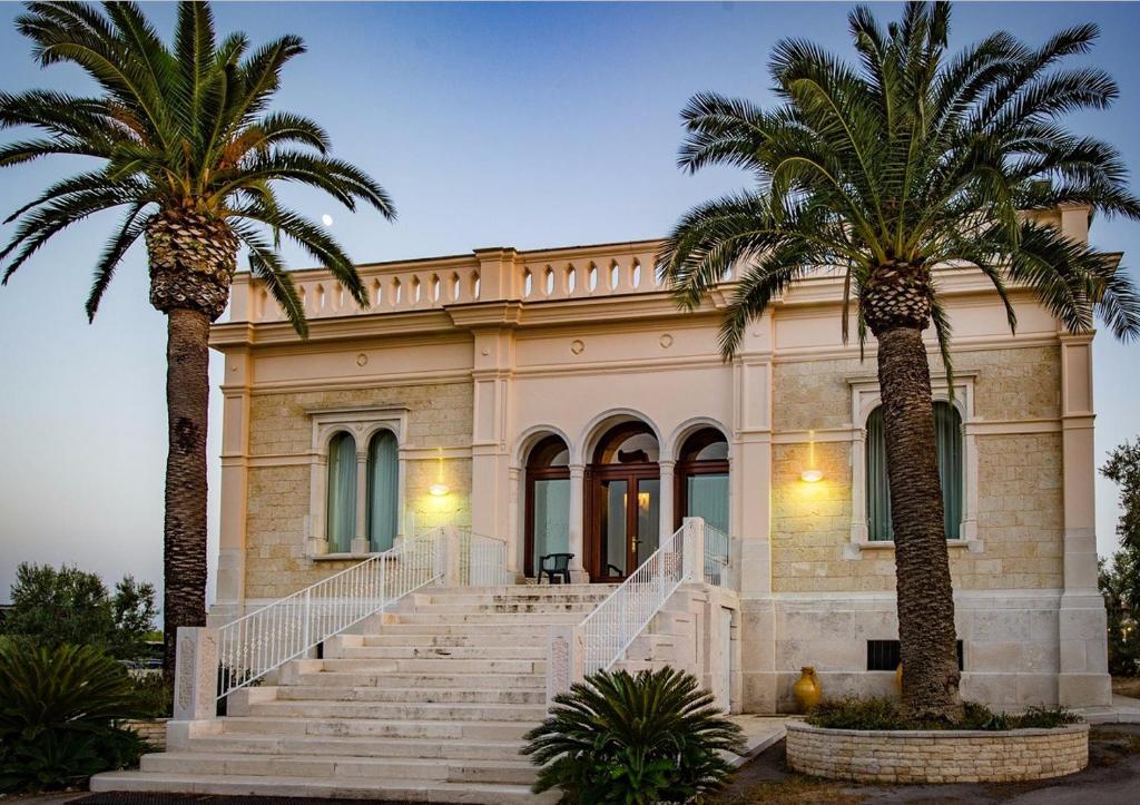 a building with two palm trees in front of it at Tenuta Lama Gorga in Trani