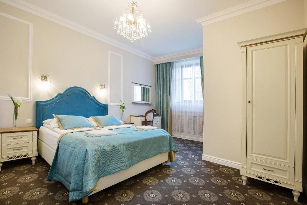 ein Schlafzimmer mit einem blauen Bett und einem Kronleuchter in der Unterkunft Dwór Hetman in Jarosław