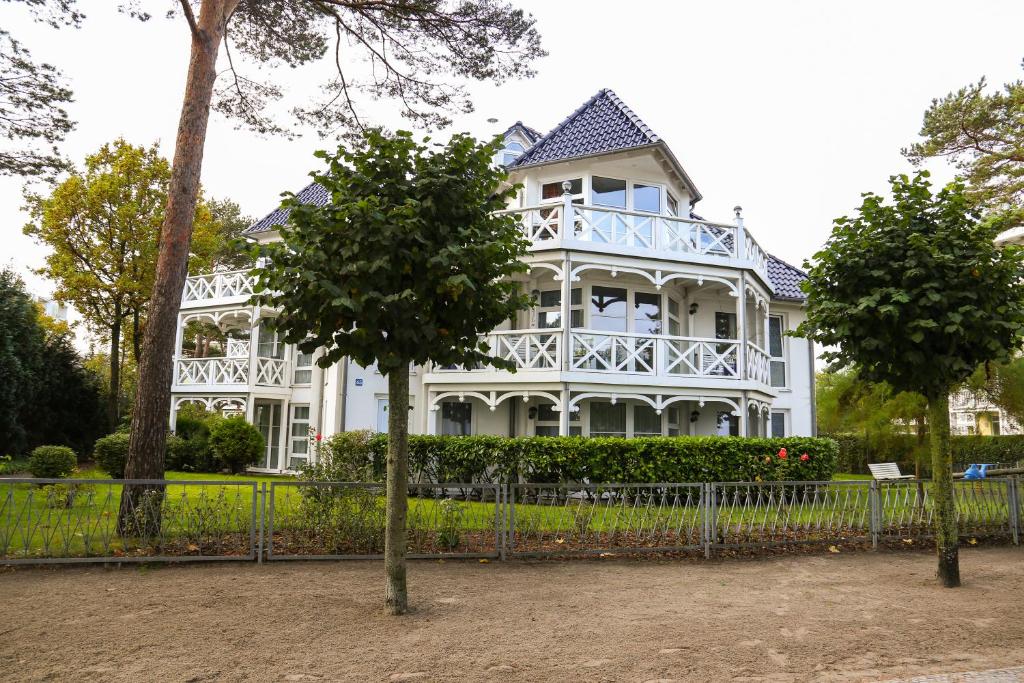 a white house with a fence and two trees at Ankerplatz Binz im Haus Strelasund in Binz