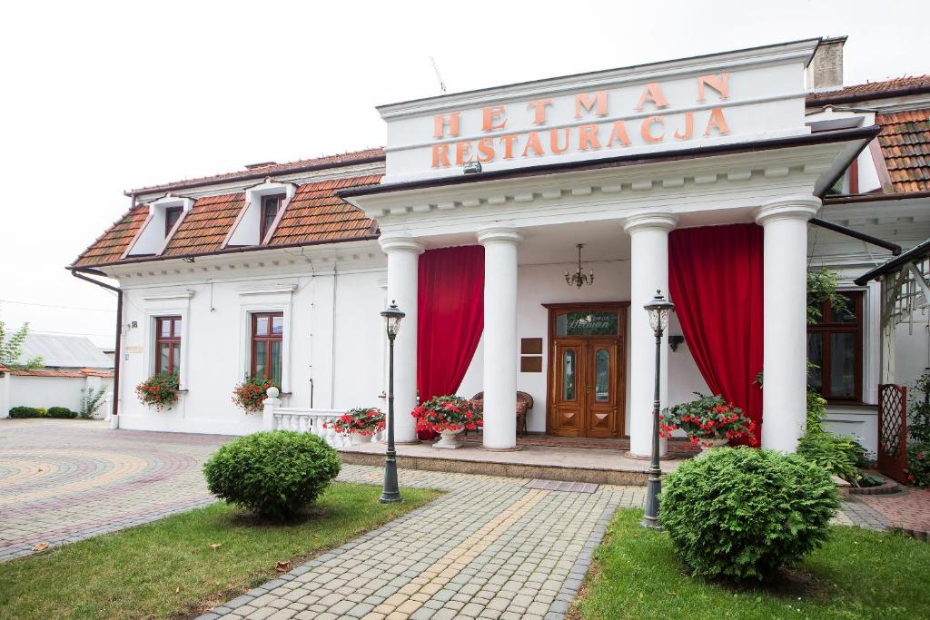 ein weißes Gebäude mit roten Vorhängen auf der Vorderseite in der Unterkunft Dwór Hetman in Jarosław