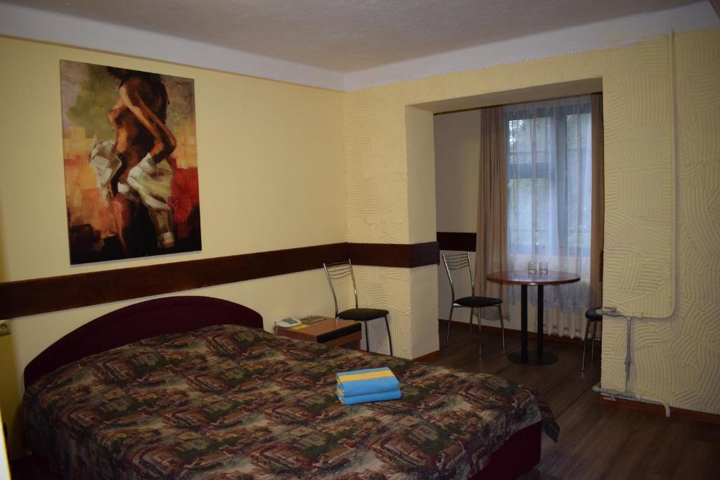 キーウにあるホテル デスナ KUTのベッド付きの客室で、壁には絵画が飾られています。