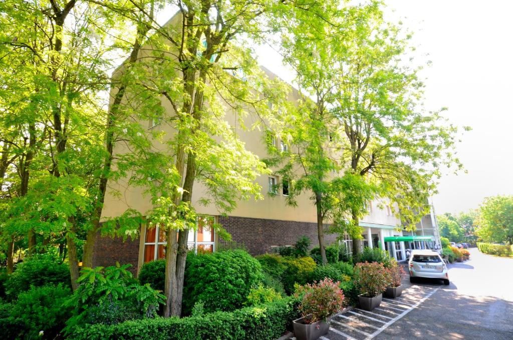 un bâtiment avec des arbres et des plantes devant lui dans l'établissement Greenhotels Roissy Parc des Expositions, à Tremblay-en-France