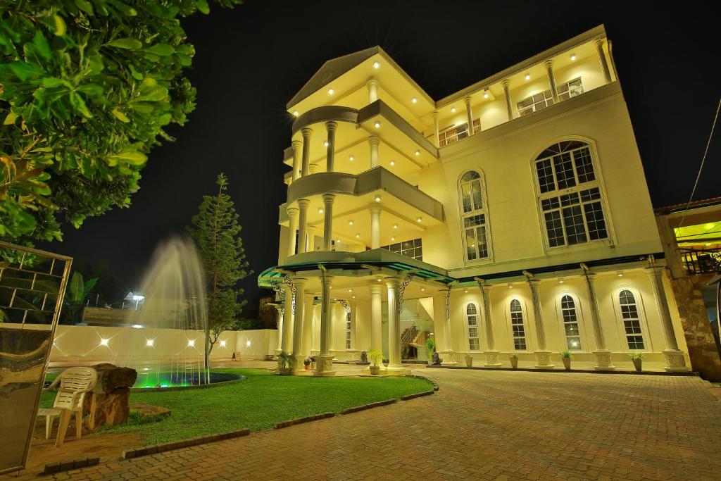 a large building with a fountain in front of it at Navro Beach Resort in Panadura