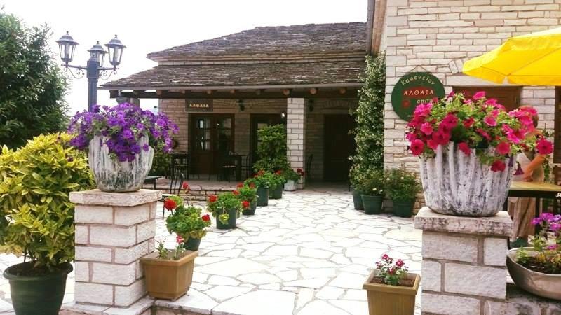 a patio with flowers in flower pots in front of a building at Althea Guesthouse in Ano Pedina