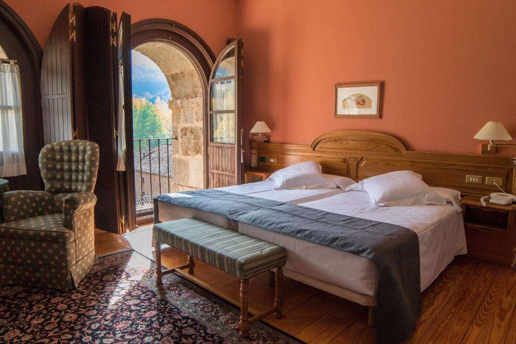 1 dormitorio con 1 cama, 1 silla y 1 ventana en Hostería del Monasterio de San Millan, en San Millán de la Cogolla