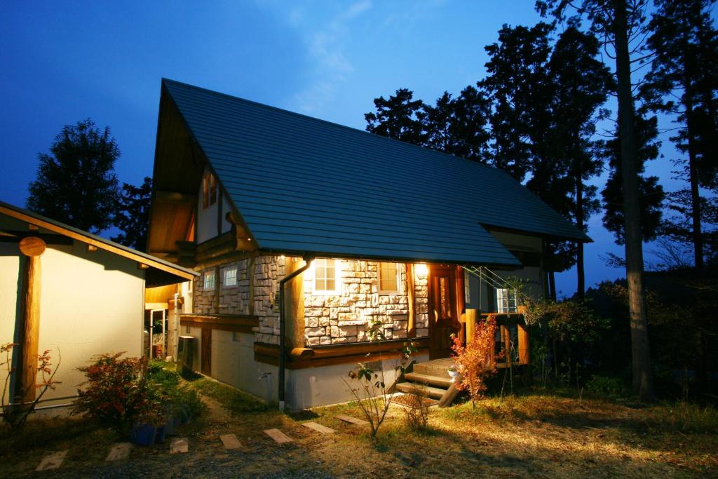 ein Haus mit einem blauen Dach mit Lichtern drauf in der Unterkunft Kurokawa Mori no Cottage in Minamioguni