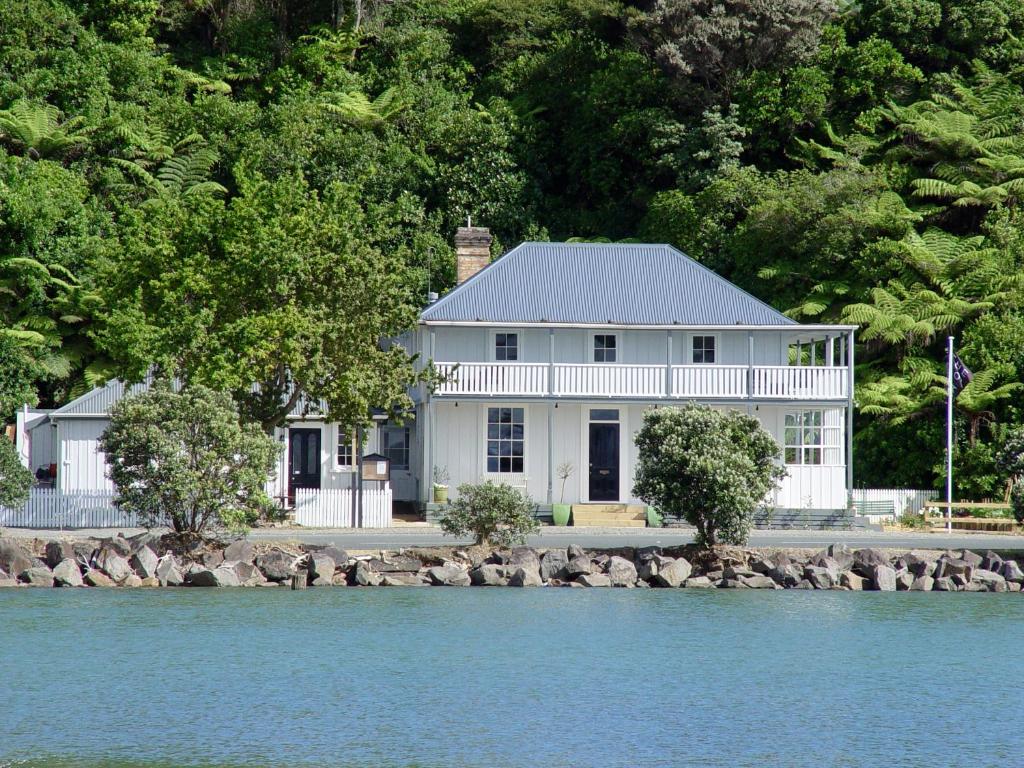 
a house with trees and a boat in the water at The Old Oak Boutique Hotel in Mangonui
