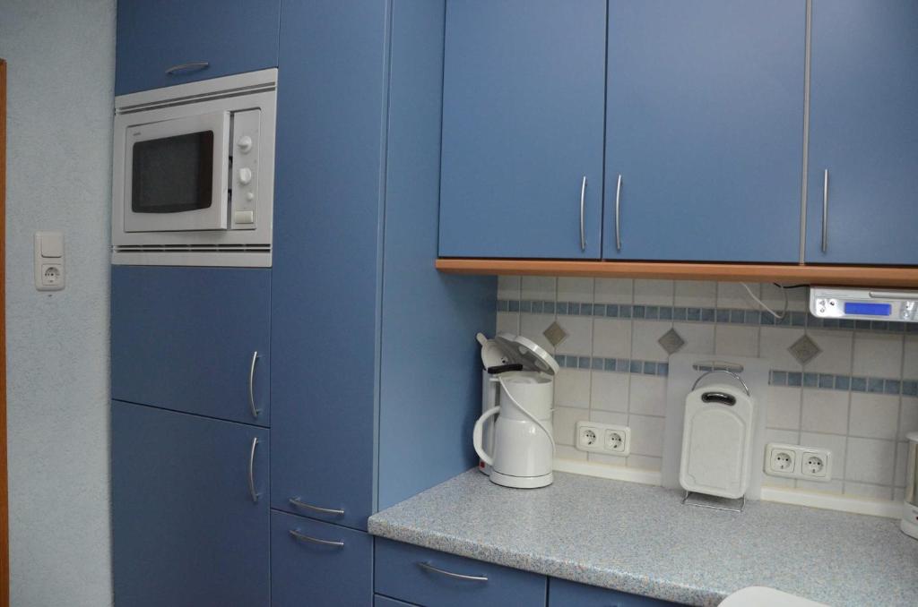 eine Küche mit blauen Schränken und einer Mikrowelle in der Unterkunft Ferienwohnung Westphal in Eschwege