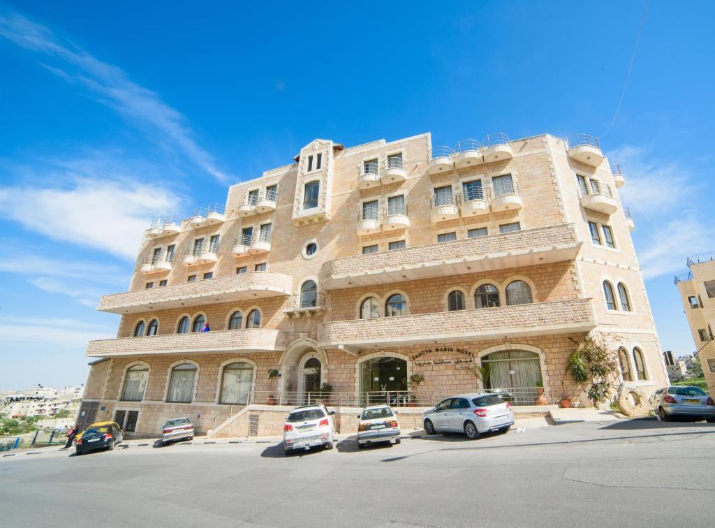 un gran edificio con coches estacionados frente a él en Sancta Maria Hotel en Bethlehem