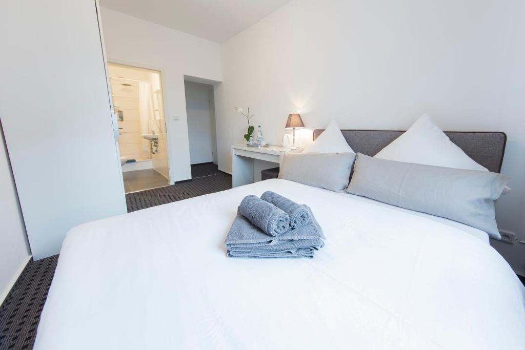 a bedroom with a white bed with towels on it at Berolina Haus in Düsseldorf