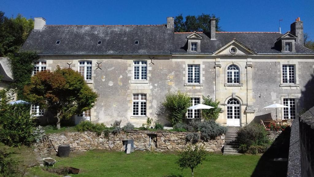 una vieja casa de piedra con un patio delante en Manoir de La Fontaine Du Chêne en Coutures