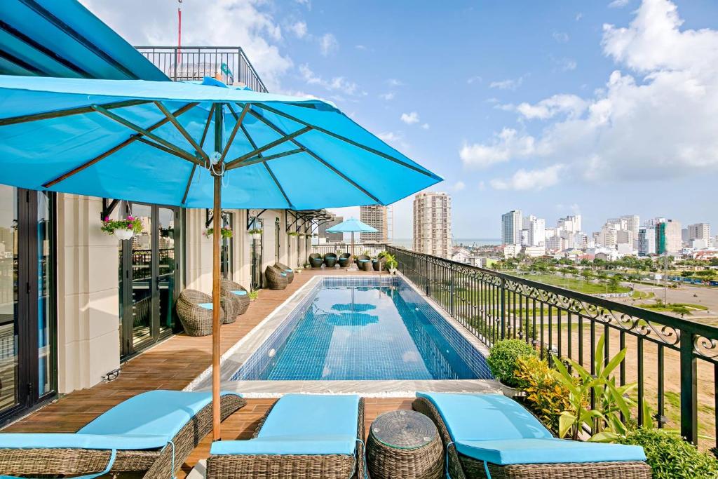 einen Balkon mit einem Pool und einem blauen Sonnenschirm in der Unterkunft The Herriott Hotel & Suite in Đà Nẵng