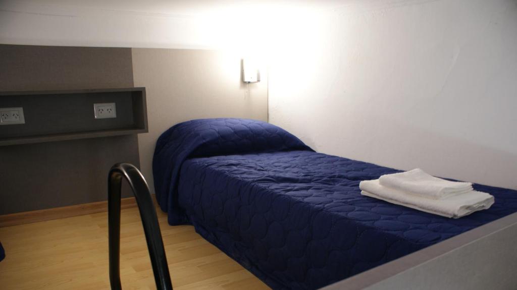 ein kleines Bett mit blauer Decke in einem Zimmer in der Unterkunft Departamento Estudio 1 in Neuquén
