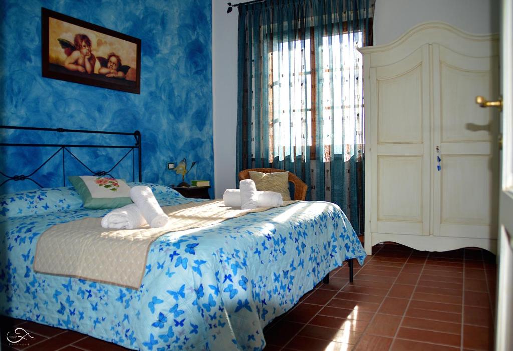 sypialnia z łóżkiem z niebieskimi ścianami i oknem w obiekcie Agriturismo La Spiga w mieście Montecatini Val di Cecina