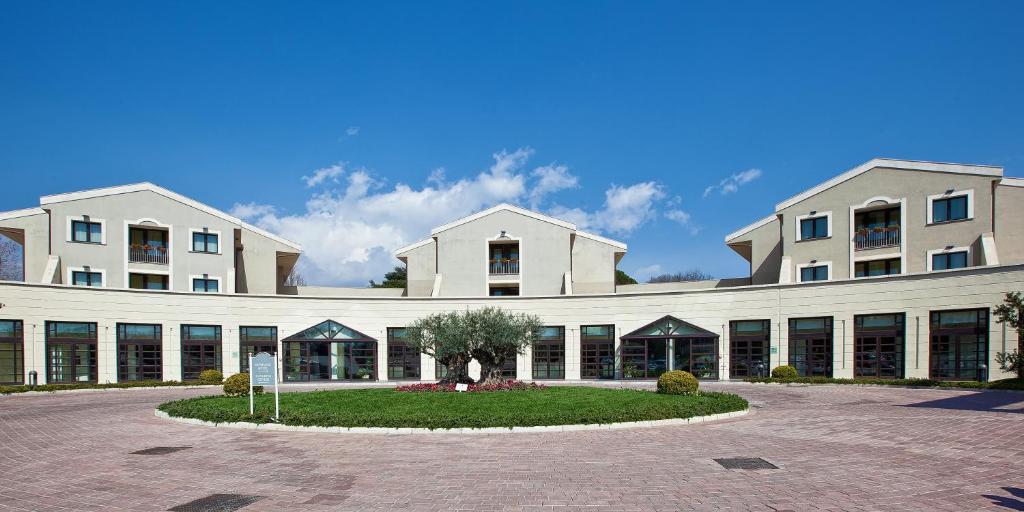 um grande edifício branco com um pátio em frente em Grand Hotel Villa Itria Congress & Spa em Viagrande