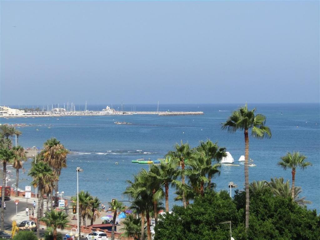 a view of a beach with palm trees and the ocean at Luxury beachfront apartment in Benalmadena Costa in Benalmádena