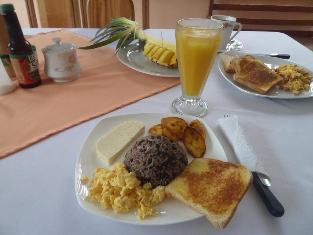 una mesa con dos platos de desayuno y un vaso de zumo de naranja en Posada Rural Río Celeste, en Rio Celeste