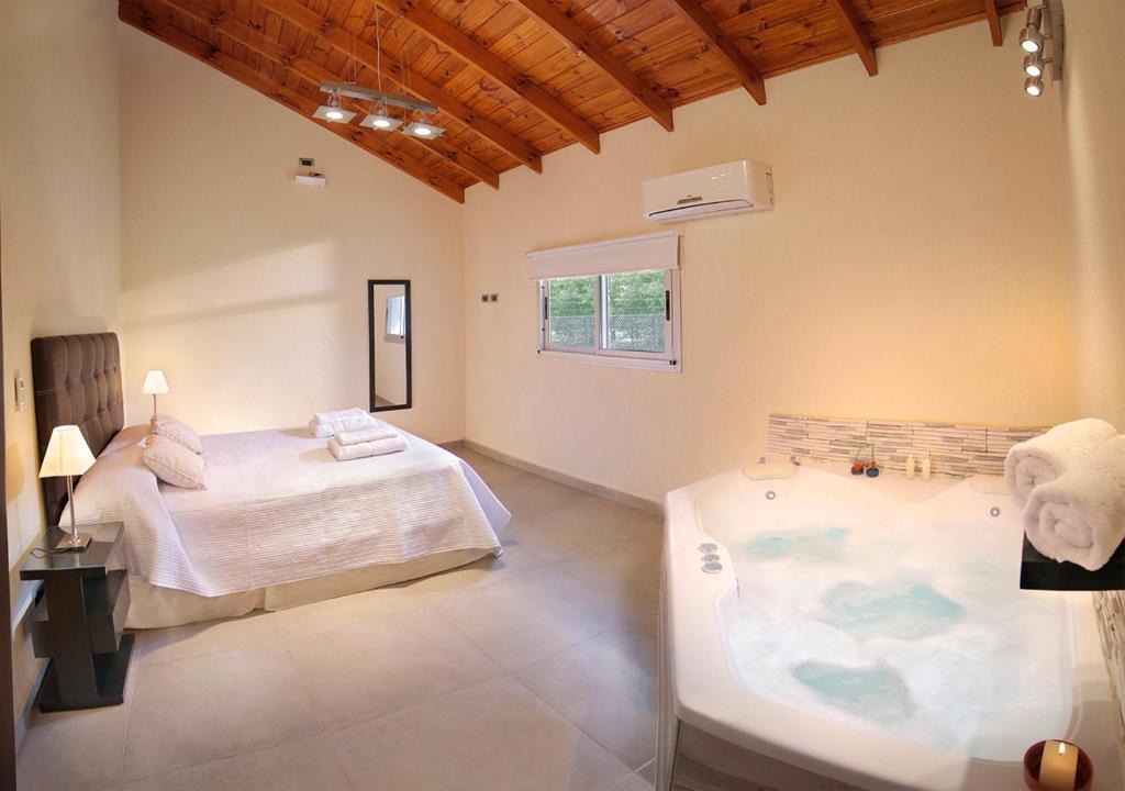 a bedroom with a bed and a tub in it at Altos del Rio (Solo parejas) in Los Reartes