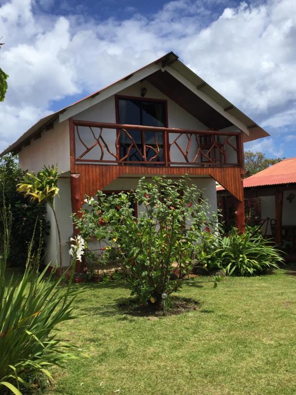 a house with a balcony on top of a yard at Cabanas Hinariru Nui in Hanga Roa