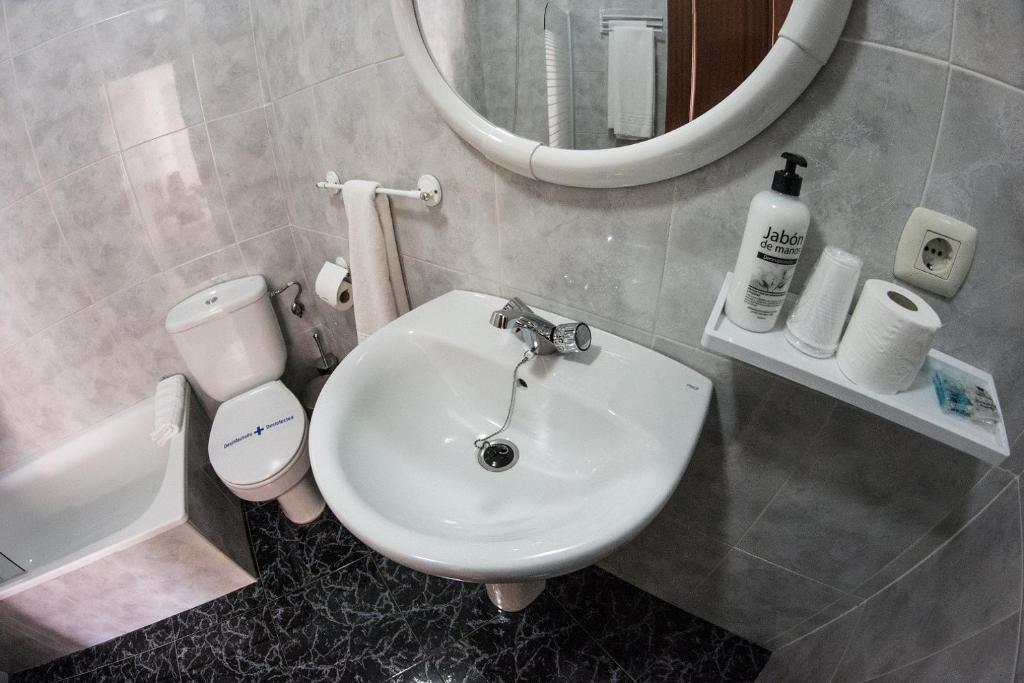 a bathroom with a sink and a toilet and a mirror at Hostal Caminito del Rey in Alora