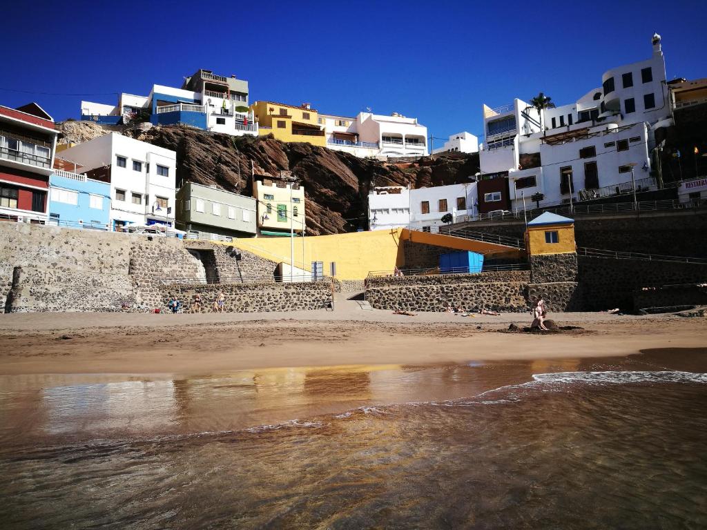 una persona de pie en una playa con edificios en el fondo en La Casa de Sardina en Sardina