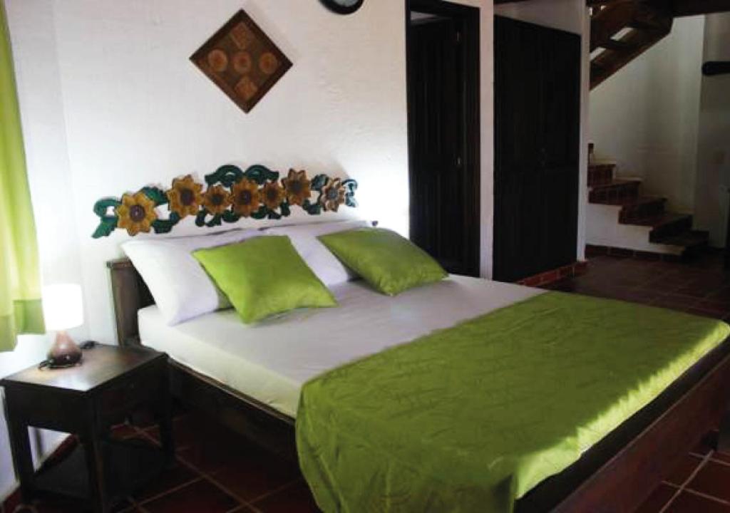 a bedroom with a large bed with green sheets at Hotel Cristo Rey Campestre in Los Santos