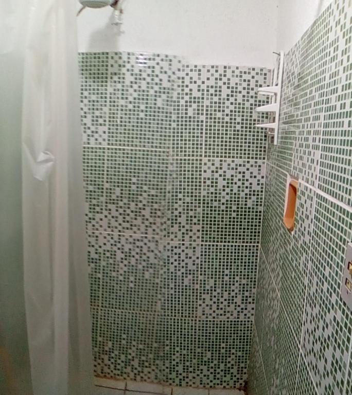 a bathroom with a shower with green and white tiles at Hostel Casa Shamballa in Camburi