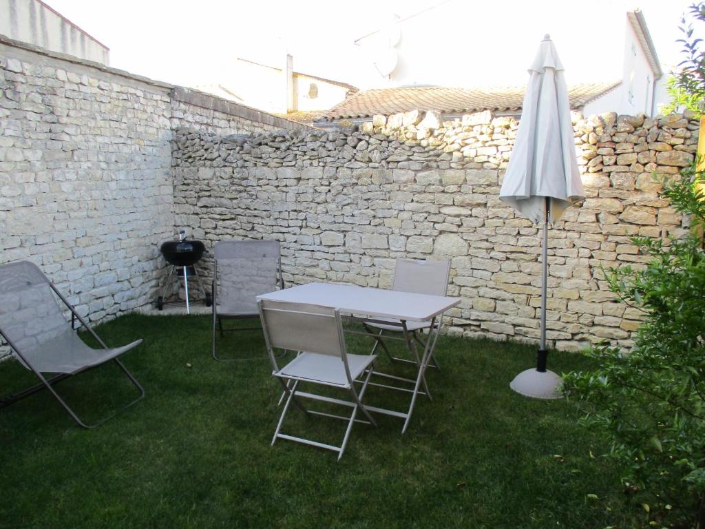 サント・マリー・ド・レにあるSTUDIO 2 PERS PROCHE PLAGE ET COMMERCESの庭にテーブルと椅子、傘