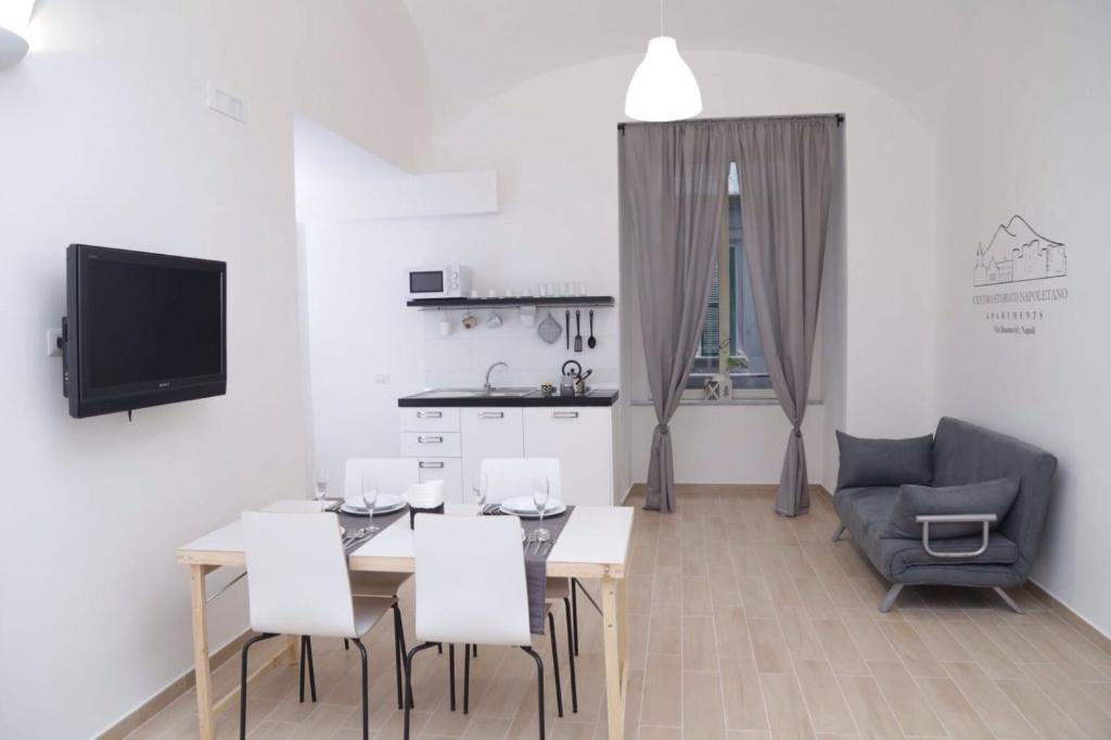 - un salon avec une table, des chaises et une télévision dans l'établissement Centro Storico Napoletano, à Naples