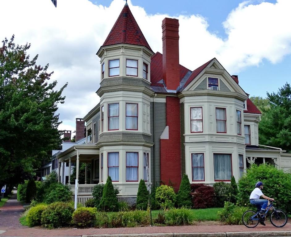 una persona montando una bicicleta delante de una casa en Maine Victorian Mansion, en Saco