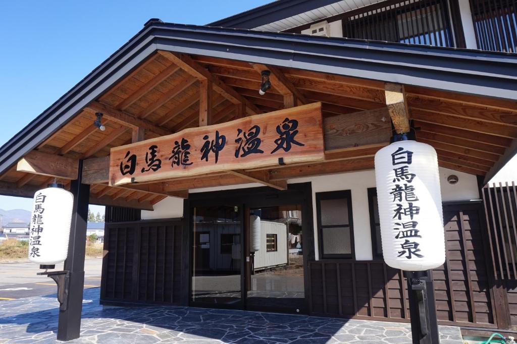 un edificio con letreros en la parte delantera en Hakuba Ryujin Onsen, en Hakuba