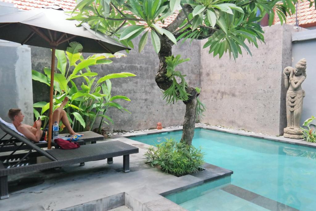 a man sitting in a chair next to a swimming pool at Duyung Homestay in Sanur