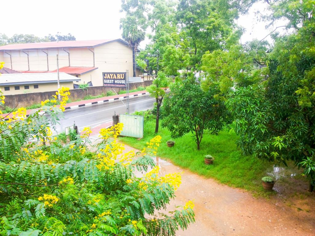 a view of a street with trees and yellow flowers at Jayaru Guest House in Polonnaruwa