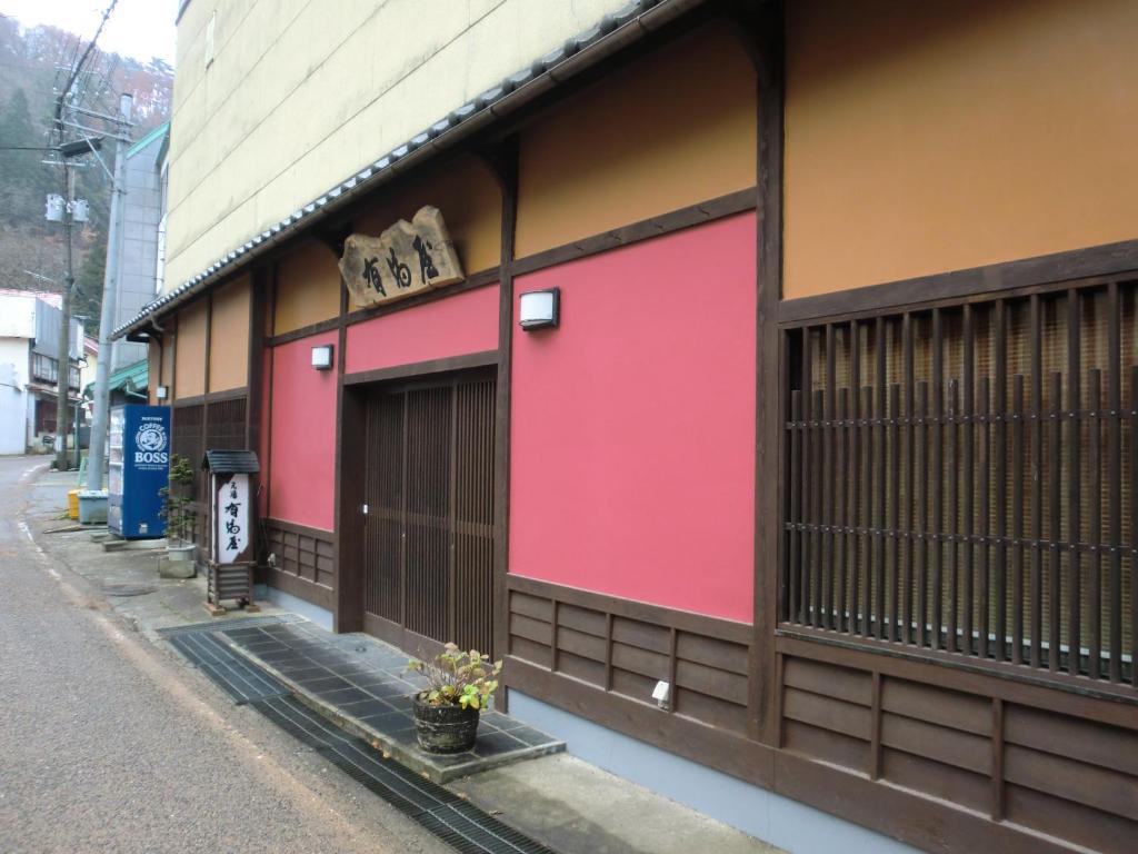 un edificio con pintura rosa al lado de una calle en Motoyu Arimaya, en Aizuwakamatsu